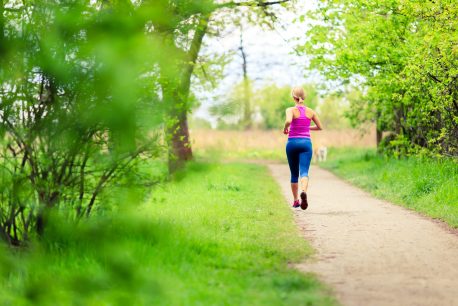 Woman runner running and walking in park, summer nature, exercising in bright forest outdoors